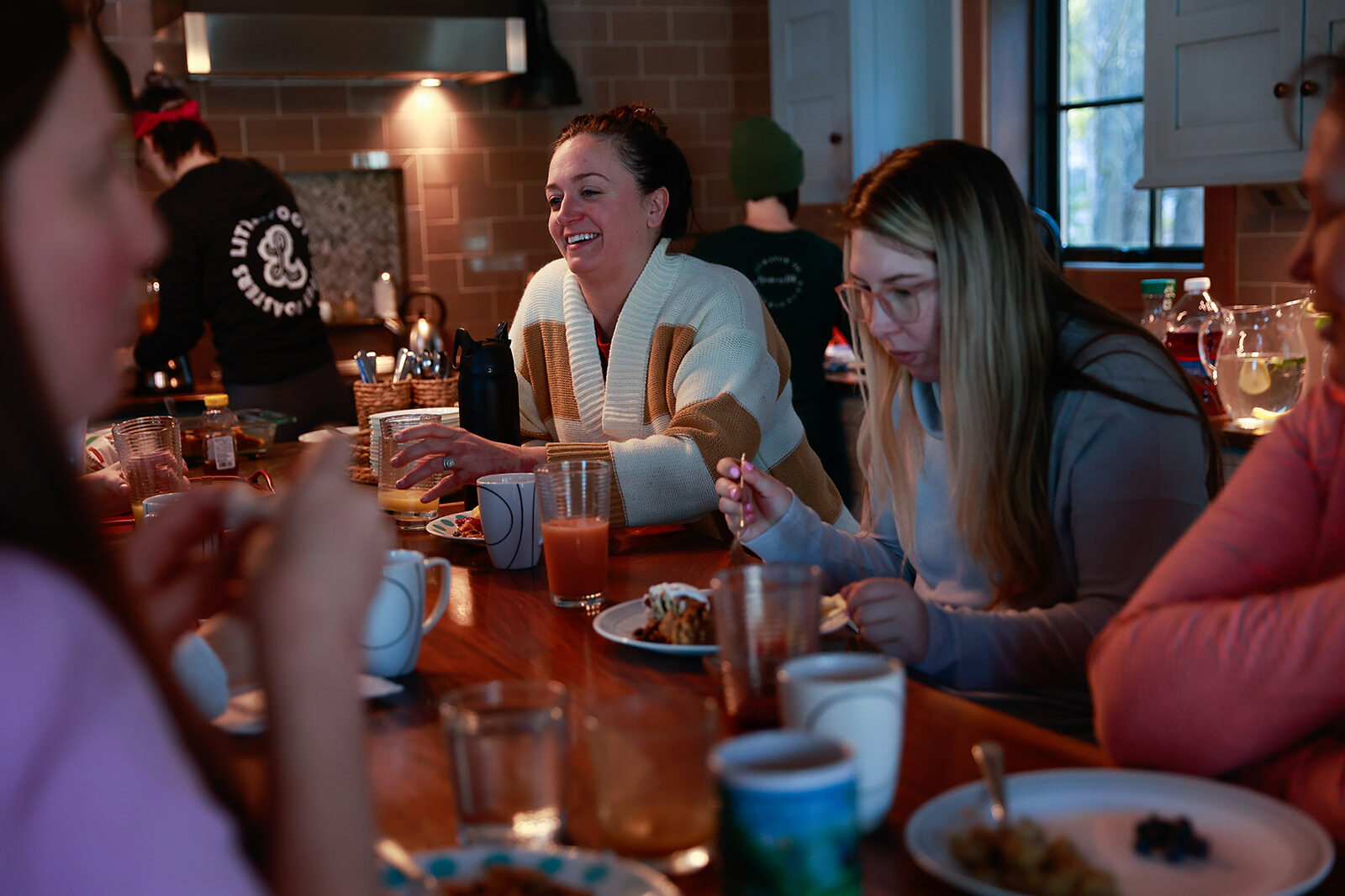 A long table of women eating dinner together, mid-conversation and laughing.